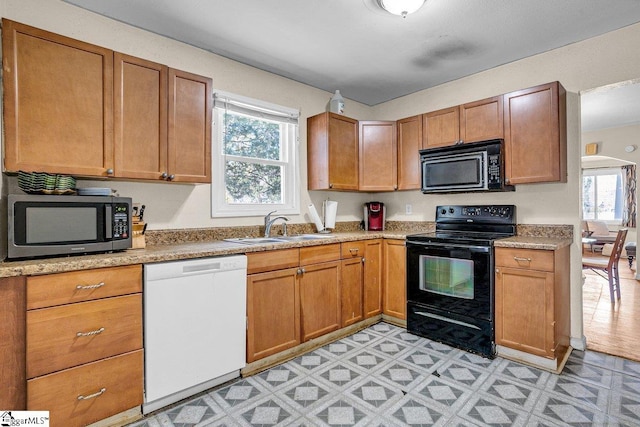 kitchen with a sink, light floors, black appliances, and light countertops