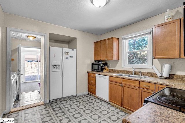 kitchen with a sink, brown cabinets, light floors, and black appliances