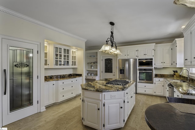 kitchen with dark stone countertops, light wood-style flooring, appliances with stainless steel finishes, and a sink