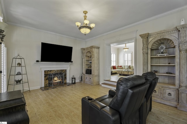 living area with a chandelier, ornamental molding, a fireplace, and wood finished floors