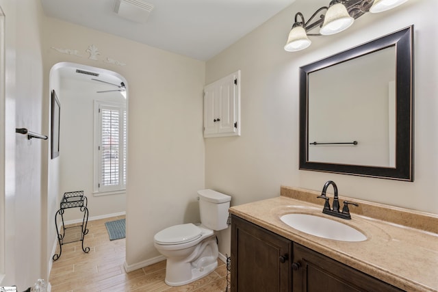 bathroom with visible vents, toilet, wood finished floors, vanity, and a ceiling fan