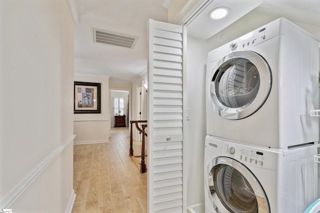 laundry area with visible vents, crown molding, light wood finished floors, stacked washer / drying machine, and laundry area