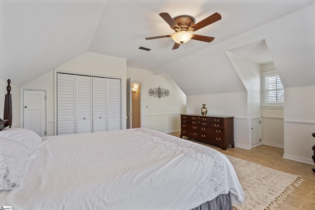 bedroom featuring visible vents, light wood finished floors, lofted ceiling, ceiling fan, and a closet