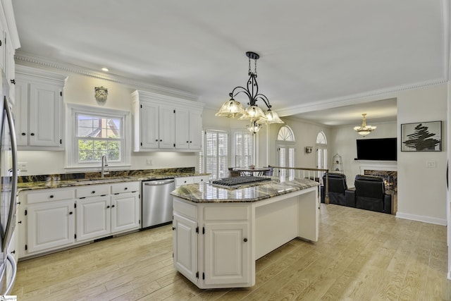 kitchen featuring light wood-style flooring, a sink, a kitchen island, stainless steel dishwasher, and dark stone counters