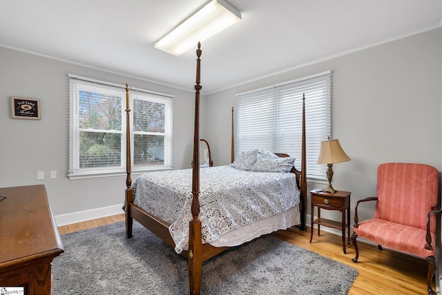 bedroom with crown molding, wood finished floors, and baseboards