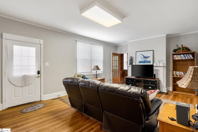 living room featuring crown molding, light wood-style flooring, visible vents, and baseboards