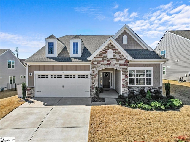 craftsman-style home featuring board and batten siding, a shingled roof, concrete driveway, stone siding, and an attached garage