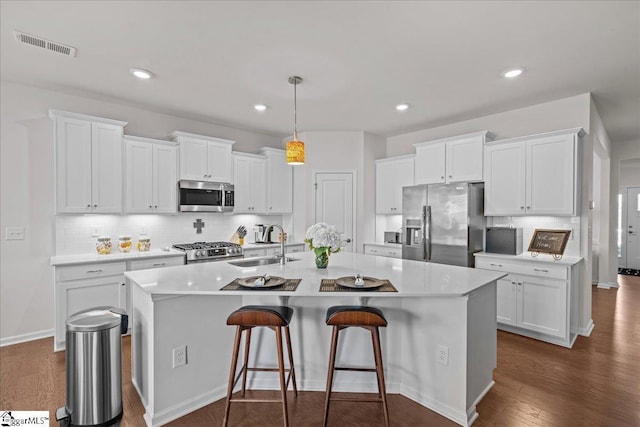 kitchen with a sink, visible vents, appliances with stainless steel finishes, and dark wood-style flooring