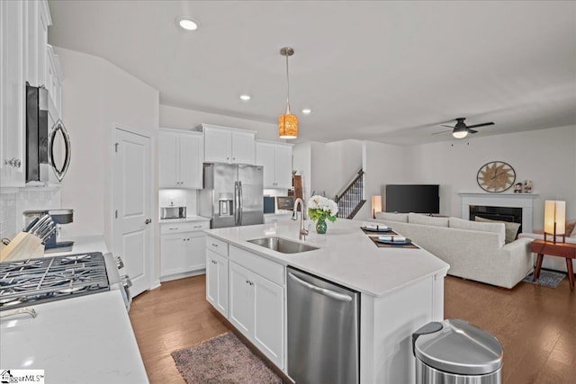 kitchen featuring a sink, appliances with stainless steel finishes, a fireplace, and light wood finished floors