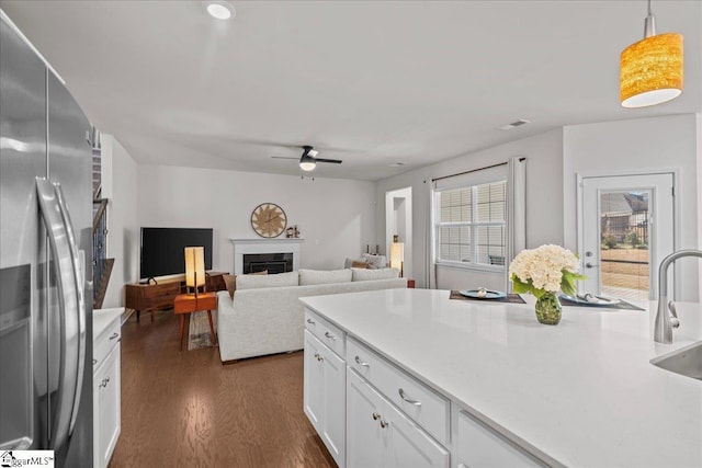 kitchen featuring dark wood-type flooring, light countertops, a fireplace, stainless steel refrigerator with ice dispenser, and white cabinetry