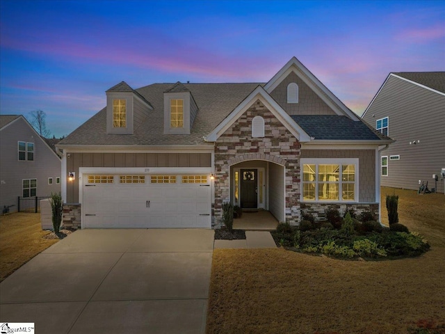 view of front of property featuring stone siding, roof with shingles, board and batten siding, concrete driveway, and a garage