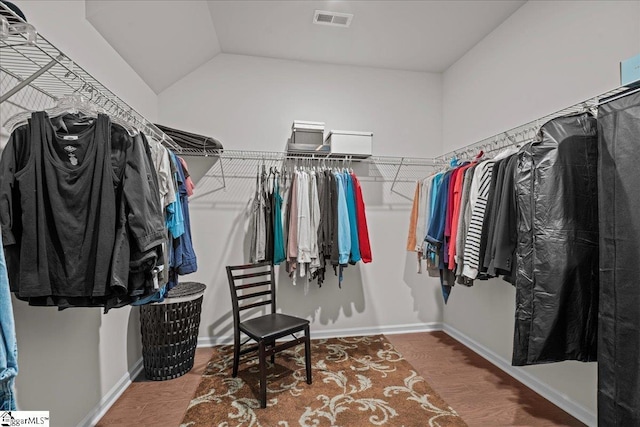 walk in closet with vaulted ceiling, visible vents, and wood finished floors