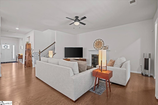 living area with visible vents, wood finished floors, stairs, and a tile fireplace