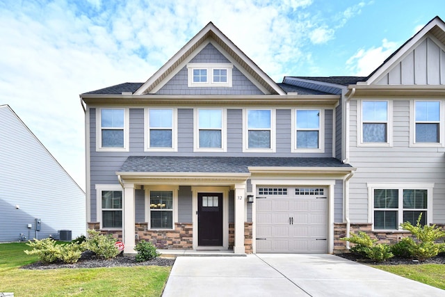 view of front of house with concrete driveway, an attached garage, board and batten siding, and stone siding