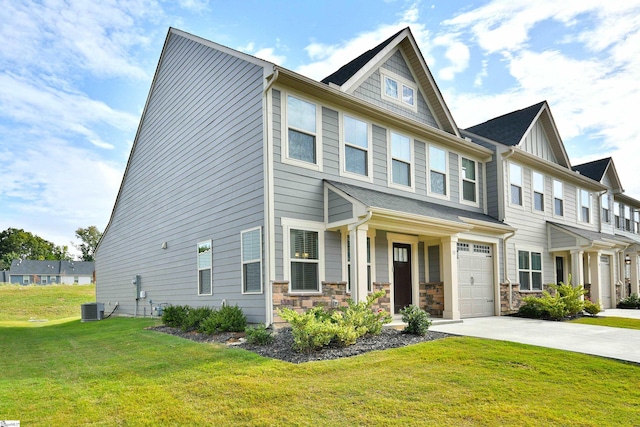 view of property featuring a front lawn, concrete driveway, central AC, stone siding, and an attached garage