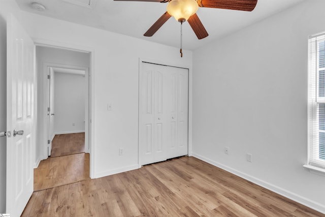 unfurnished bedroom with baseboards, multiple windows, a closet, and light wood finished floors