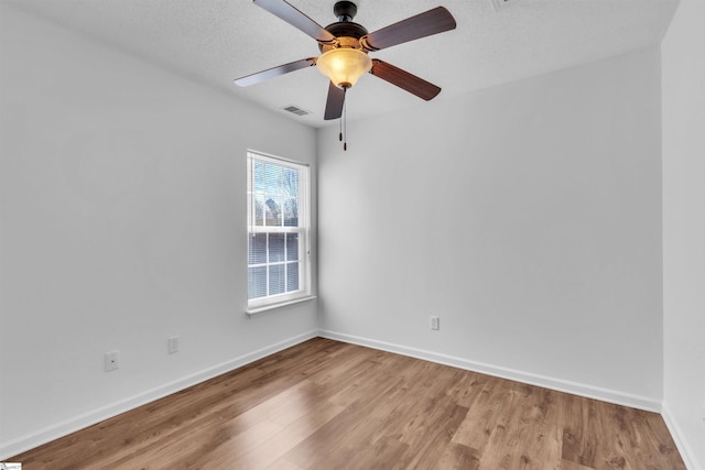 spare room with visible vents, a textured ceiling, wood finished floors, baseboards, and ceiling fan