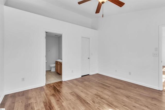 unfurnished bedroom featuring light wood-type flooring, connected bathroom, baseboards, and a ceiling fan