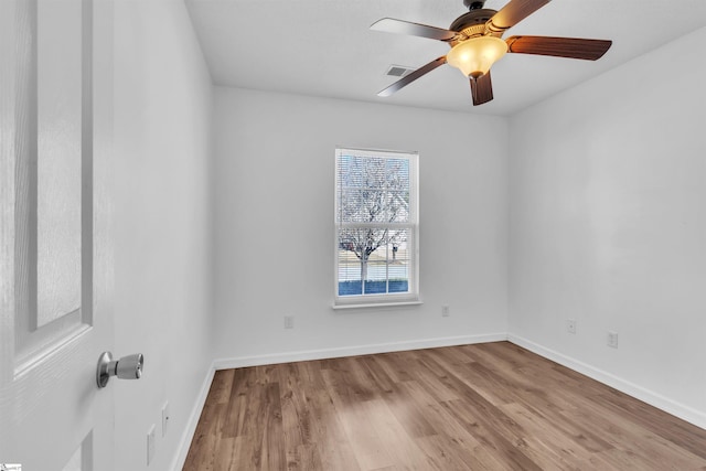 empty room with wood finished floors, visible vents, and baseboards