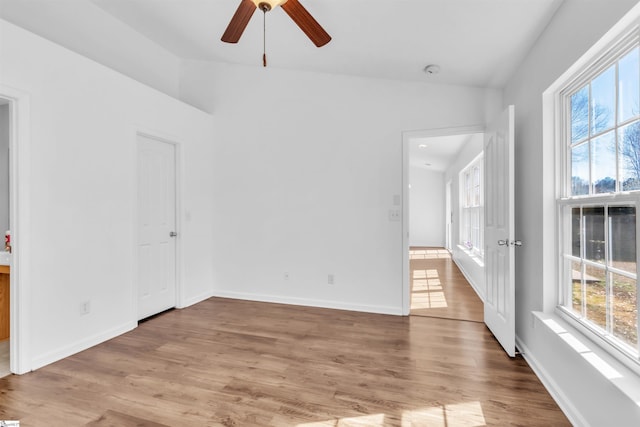 empty room featuring a wealth of natural light, baseboards, and light wood finished floors