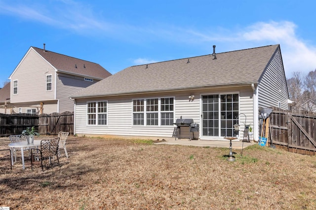 rear view of property featuring a yard, fence, a shingled roof, and a patio area