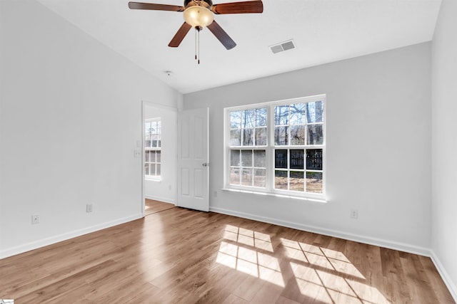 unfurnished room featuring visible vents, baseboards, wood finished floors, and vaulted ceiling