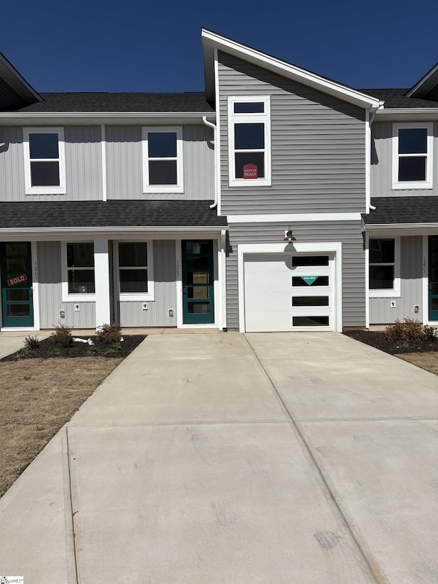 view of front of home with concrete driveway, a garage, and a shingled roof