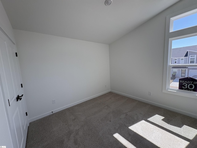 carpeted spare room with baseboards and vaulted ceiling