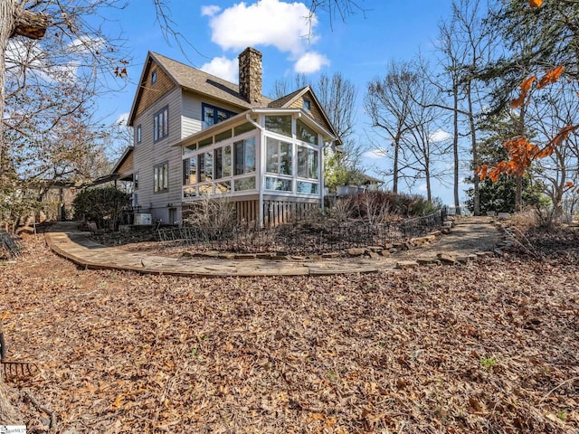 rear view of house with a chimney and a sunroom