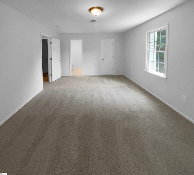 carpeted empty room featuring baseboards and visible vents