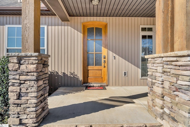 view of exterior entry featuring stone siding and a shingled roof