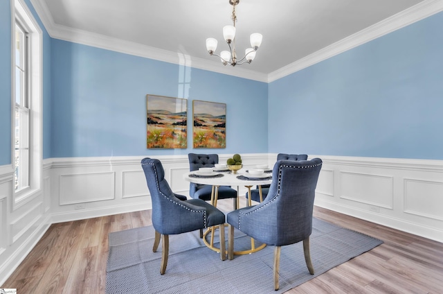 dining room featuring ornamental molding, wood finished floors, wainscoting, and a chandelier