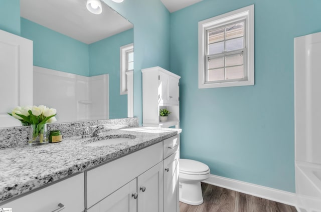 bathroom with a healthy amount of sunlight, toilet, baseboards, and wood finished floors