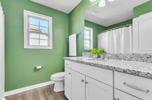 bathroom featuring visible vents, baseboards, toilet, wood finished floors, and vanity