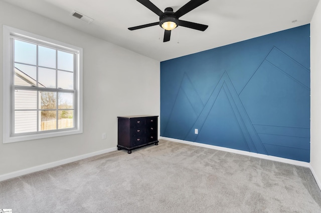 carpeted empty room with baseboards, visible vents, and ceiling fan