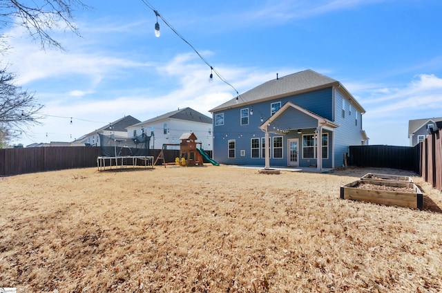 back of property with a playground, a trampoline, a fenced backyard, a garden, and a patio