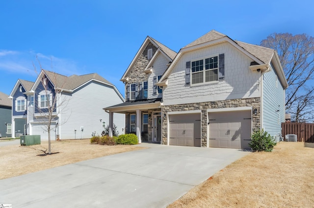 view of front of property featuring driveway, an attached garage, central AC, stone siding, and board and batten siding