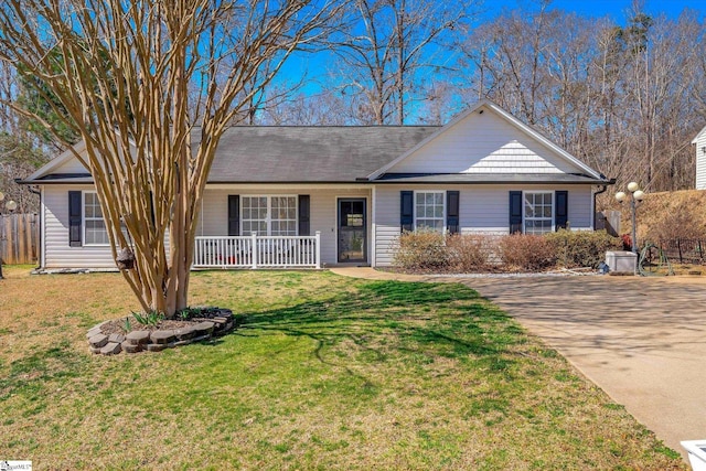 ranch-style house featuring covered porch, a front lawn, and fence