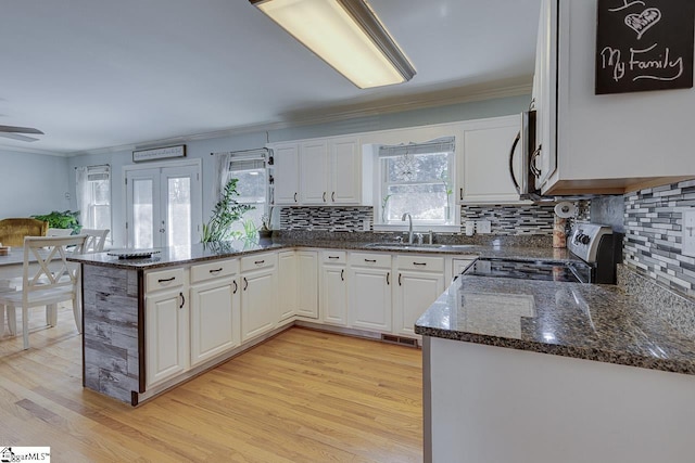 kitchen with a sink, a peninsula, white cabinets, and stainless steel appliances