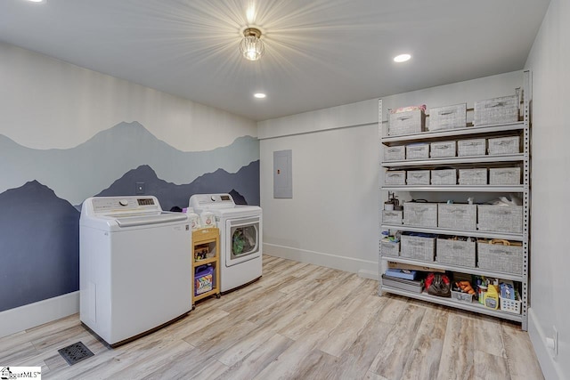 washroom featuring laundry area, electric panel, wood finished floors, and washing machine and clothes dryer