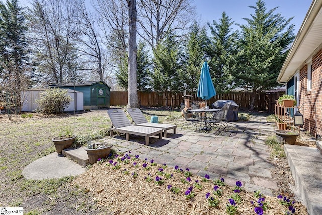 view of patio / terrace featuring an outbuilding, a grill, a storage shed, and a fenced backyard