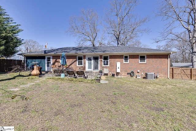 back of property with fence, central AC, entry steps, a lawn, and brick siding