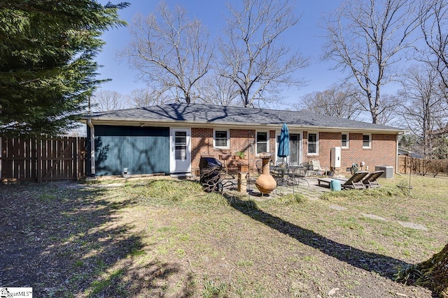 rear view of house with brick siding, a patio area, central AC, and fence