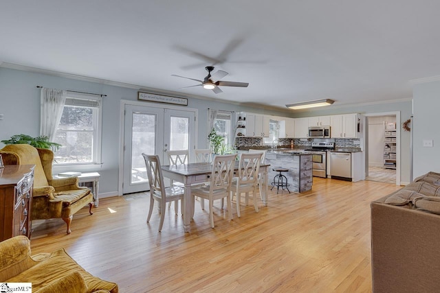 dining area with a ceiling fan, baseboards, light wood finished floors, french doors, and crown molding