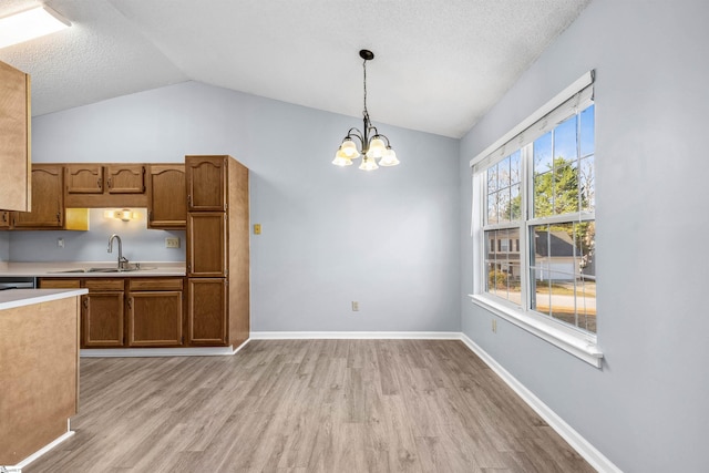 kitchen with a sink, light wood-type flooring, decorative light fixtures, and light countertops