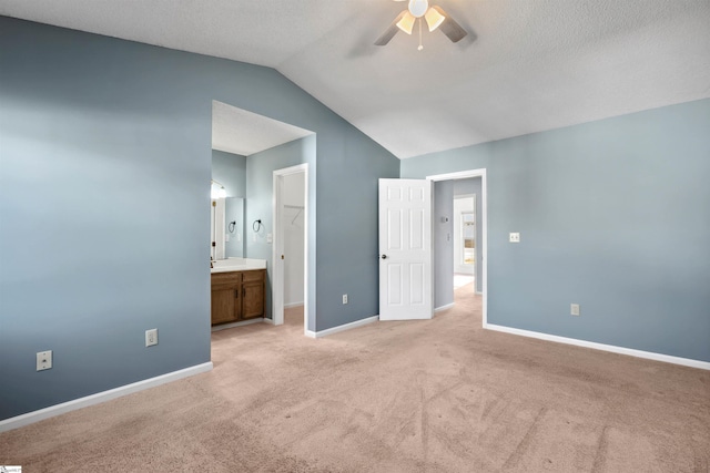 unfurnished bedroom with ceiling fan, baseboards, lofted ceiling, light carpet, and ensuite bath