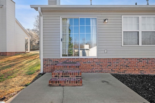 entrance to property featuring brick siding and a chimney