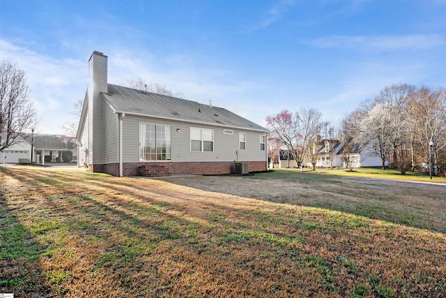 rear view of property with a lawn, central AC unit, and a chimney