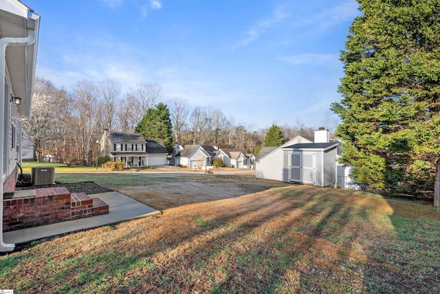 view of yard with an outdoor structure, a storage unit, a residential view, and central AC