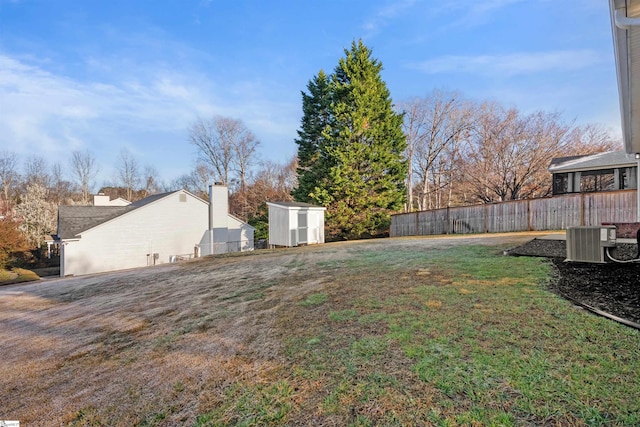 view of yard with central AC unit, a storage shed, an outdoor structure, and fence